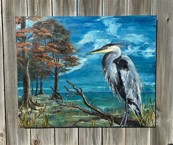 Oil painting of a great blue heron standing among cypress trees on a swamp shoreline, under a swirling blue sky.